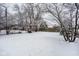 Spacious backyard covered in snow, surrounded by trees, and a wooden fence at 5736 Central Ave, Indianapolis, IN 46220
