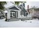 Charming gray home featuring a covered porch, white columns, and manicured landscaping dusted with snow at 5736 Central Ave, Indianapolis, IN 46220