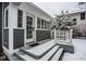 Inviting sunroom entrance featuring gray siding, white trim, and snowy steps, creating a cozy winter scene at 5736 Central Ave, Indianapolis, IN 46220