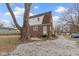 Backyard with a partial view of the brick home, a large tree, and stone driveway at 5814 Beechwood Ave, Indianapolis, IN 46219