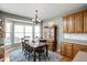 Well-lit dining room with a large window, chandelier, wooden table, and cabinet at 649 Hummingbird Dr, Brownsburg, IN 46112