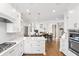 Open kitchen featuring white cabinets, quartz countertops, stainless steel appliances, and hardwood flooring at 9914 Springstone Rd, Fishers, IN 46055