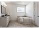 Bright bathroom featuring double sink granite vanity, soaking tub, and white paneled walls at 10541 Titan Run, Carmel, IN 46032