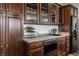 Wet bar with dark wood cabinets, wine rack, sink, dishwasher, and a black refrigerator at 10541 Titan Run, Carmel, IN 46032