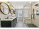 Bright bathroom with a double vanity with round mirrors and a glass-enclosed shower with a bench at 10887 Gresham Pl, Noblesville, IN 46060