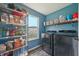 A well-organized laundry room, with light blue walls, featuring stainless steel shelving, a window and front loading machines at 10887 Gresham Pl, Noblesville, IN 46060