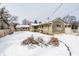 View of the backyard in winter with snow covering the area and stone home exterior at 1401 Castle Ave, Indianapolis, IN 46227
