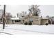 A single-story home featuring a stone facade, sidewalk, and a snow-covered yard at 1401 Castle Ave, Indianapolis, IN 46227