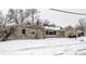 A single-story home featuring a stone facade, sidewalk, and a snow-covered yard at 1401 Castle Ave, Indianapolis, IN 46227