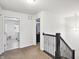 Upstairs hallway with dark-stained banister, laundry room access and open door to bedroom at 2091 Creek Bank Dr, Columbus, IN 47201
