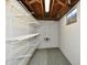 Unfinished basement features wooden ceiling beams, white-painted walls, storage shelving, and mixed flooring at 2521 Beechcrest Dr, Indianapolis, IN 46203