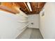 Unfinished basement with exposed wooden ceiling beams, white-painted walls, storage shelving, and mixed flooring at 2521 Beechcrest Dr, Indianapolis, IN 46203