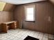 Small bedroom space featuring wood paneling, a desk, and a single window at 317 S Harris Ave, Indianapolis, IN 46222