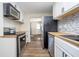 Galley kitchen featuring stainless steel appliances, butcher block countertops, and mosaic backsplash at 4623 Clark St, Anderson, IN 46013