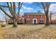 Charming two-story red brick home with blue shutters surrounded by mature trees and a green front lawn at 4783 Briarwood Trce, Carmel, IN 46033