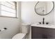 A powder room featuring a modern vanity, round mirror, and black hardware at 5210 Ashbourne Ln, Indianapolis, IN 46226