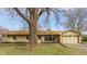 Charming single-story home with a tan brick exterior, attached garage, and mature landscaping at 5210 Ashbourne Ln, Indianapolis, IN 46226