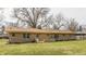 Rear exterior view of a charming brick home showcasing well-placed windows and an attached covered patio at 5210 Ashbourne Ln, Indianapolis, IN 46226