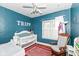 Bedroom with blue walls, a white crib, rocking chair, and sports-themed decor at 6179 Norwaldo Ave, Indianapolis, IN 46220