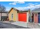 Detached garage featuring a vibrant red door complemented by the yellow exterior with solar panels at 645 E 9Th St, Indianapolis, IN 46202