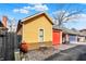 Detached yellow garage with red door with an adjacent yard and gray fence at 645 E 9Th St, Indianapolis, IN 46202