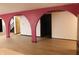 Living room with red architectural arches, white walls, and light wood-look flooring leading to stairs at 8940 Black Hawk Ln, Indianapolis, IN 46234