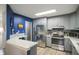 Modern kitchen with stainless steel appliances, gray cabinetry, quartz counters, and blue accent wall at 9505 Bay Vista W Dr, Indianapolis, IN 46250
