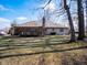 View of the home from the backyard showcasing a deck, chimney, and mature trees at 10831 Canoe Ct, Indianapolis, IN 46236