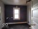 Dilapidated bedroom features dark walls, a window, and damaged flooring at 1310 E 5Th St, Muncie, IN 47302