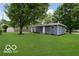 View of the backyard and house showing the lawn, mature trees, shed, and exterior at 1807 Dayton Ave, Indianapolis, IN 46203