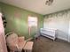 Bedroom featuring light green walls and a white crib and rocking chair at 1807 Dayton Ave, Indianapolis, IN 46203