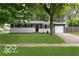 Charming single-story home with a well-maintained lawn and mature trees providing shade at 1807 Dayton Ave, Indianapolis, IN 46203
