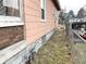 Side exterior view of the house with peach siding over a stone foundation and a visible gas meter at 1826 Mansfield St, Indianapolis, IN 46202