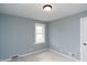 A bedroom with light gray walls, white trim, a window, and a ceiling light at 3723 N Olney St, Indianapolis, IN 46218