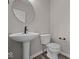 Modern powder room featuring pedestal sink, round mirror, and white toilet at 4160 Douro Trl, Westfield, IN 46062