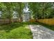 Grassy backyard, with mature trees and a gravel parking pad, enclosed by a wood fence at 4242 Winthrop Ave, Indianapolis, IN 46205