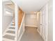 Basement hallway with wood railing staircase, grey flooring, and a white door at 520 N Parker Ave, Indianapolis, IN 46201
