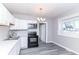 Well-lit kitchen with white cabinetry, black appliances, and gray floors at 59 E Troy Ave, Indianapolis, IN 46225
