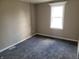 An empty bedroom features neutral paint, new carpet, and natural light from a window at 609 S Grant St, Martinsville, IN 46151