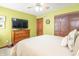 A green bedroom with a ceiling fan, dresser, and large screen TV at 6530 Grant Wood Ct, Indianapolis, IN 46256