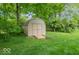 A backyard storage shed on a lush green lawn and landscaped with shady trees and shrubs at 6530 Grant Wood Ct, Indianapolis, IN 46256