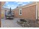 Brick patio with dining furniture next to a small, decorative pond and a brick house with a yellow door at 8401 N College Ave, Indianapolis, IN 46240