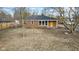 Aerial view of the exterior of a brick home featuring a yellow front door, a yard, and mature trees at 8401 N College Ave, Indianapolis, IN 46240