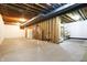 Open unfinished basement with exposed ceiling beams, stairs, shelving, and a concrete floor offering possibilities at 897 Copperwood Dr, Carmel, IN 46033