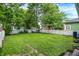 Wide backyard featuring a lush lawn, white picket fence, some mature trees, and a small wooden bench at 912 Harlan St, Indianapolis, IN 46203