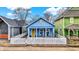 Charming blue home featuring a cozy front porch, bright yellow door, and white picket fence at 912 Harlan St, Indianapolis, IN 46203