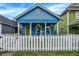 Charming blue bungalow with inviting front porch, lovely landscaping, and a classic white picket fence at 912 Harlan St, Indianapolis, IN 46203