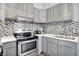 Modern kitchen featuring stainless steel appliances, grey cabinets, quartz countertops, and tiled backsplash at 912 Harlan St, Indianapolis, IN 46203