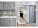 A kitchen area featuring gray cabinets, a stainless steel sink, and modern mosaic backsplash at 912 Harlan St, Indianapolis, IN 46203