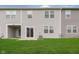 A view of the home's backyard featuring lush green grass, patio, neutral siding, and sliding glass doors at 1257 Newton St, Avon, IN 46123